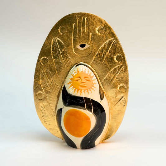 front view of hand made ceramic goddess with a gold crown 