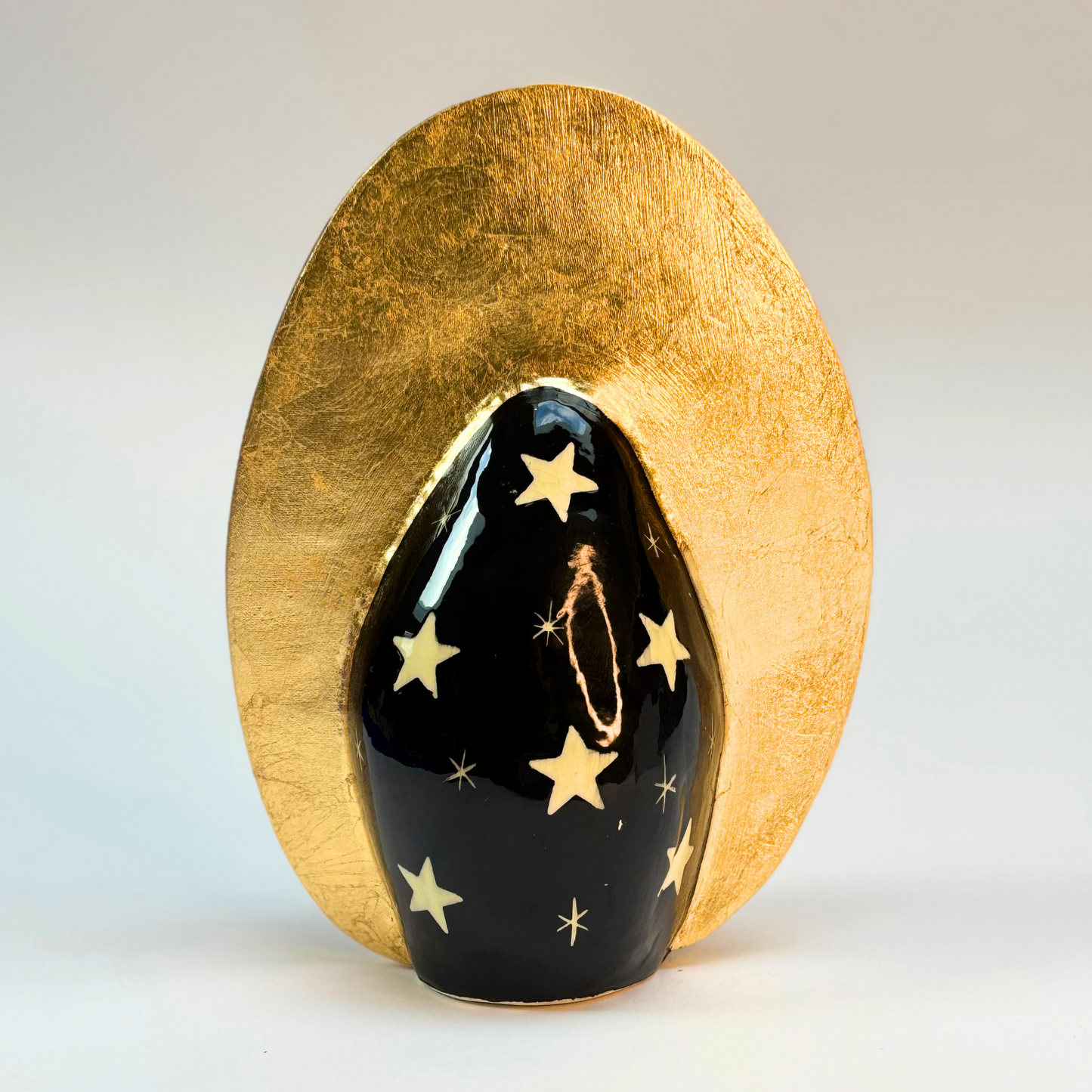 back view of ceramic goddess black ground hand painted black with white stars and gold crown surround
