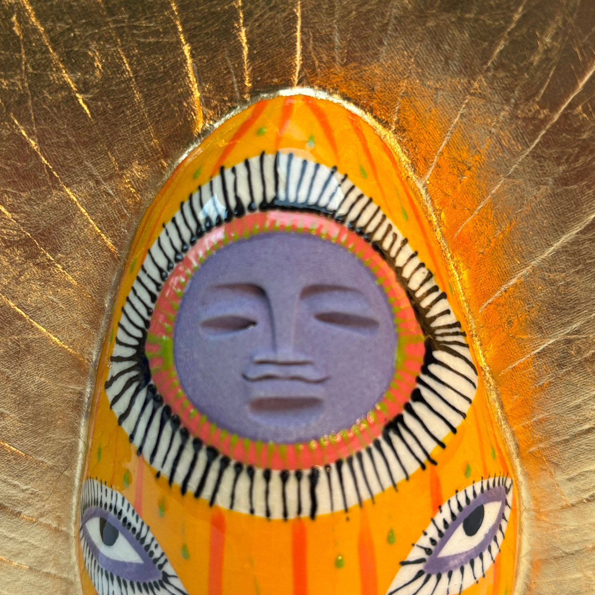 close up of smiling lavender face of the goddess with radiating gold crown and eye design
