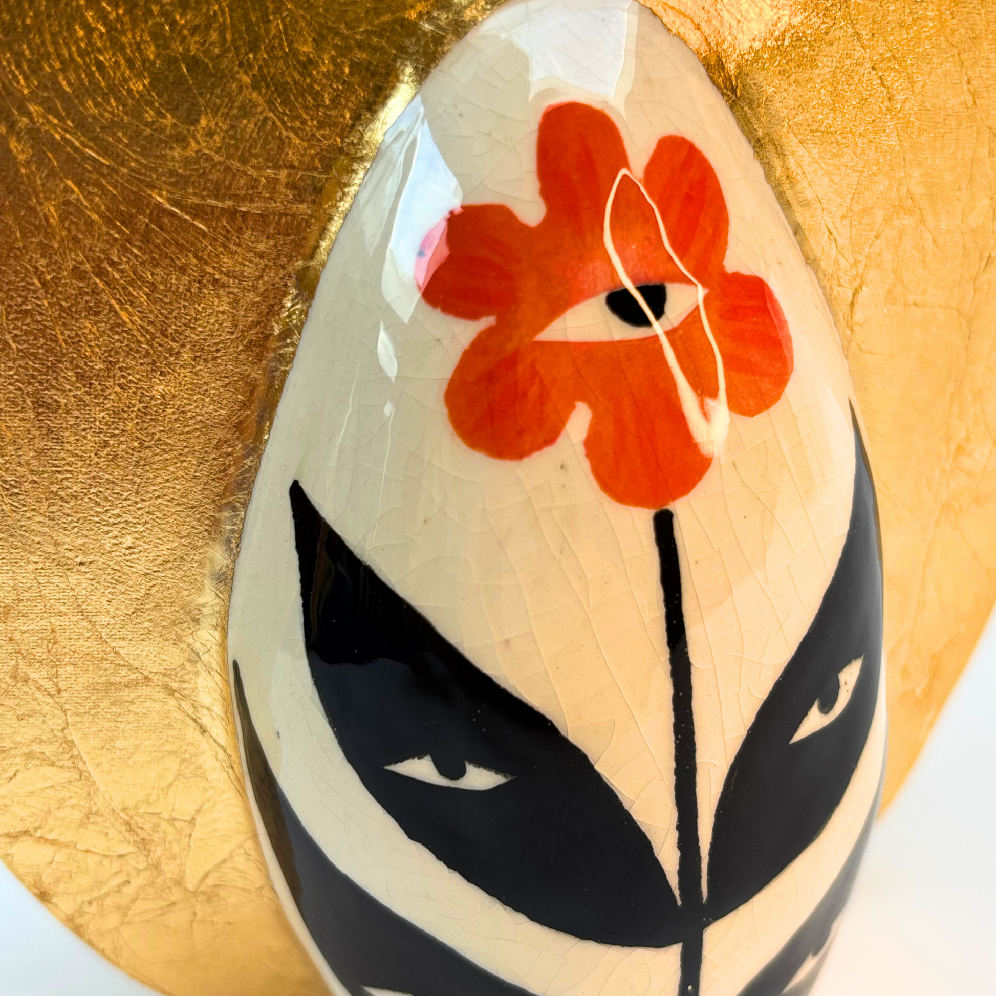 close up of peaceful flower face in orange with black leaves and eyes and the crown is smooth not embossed