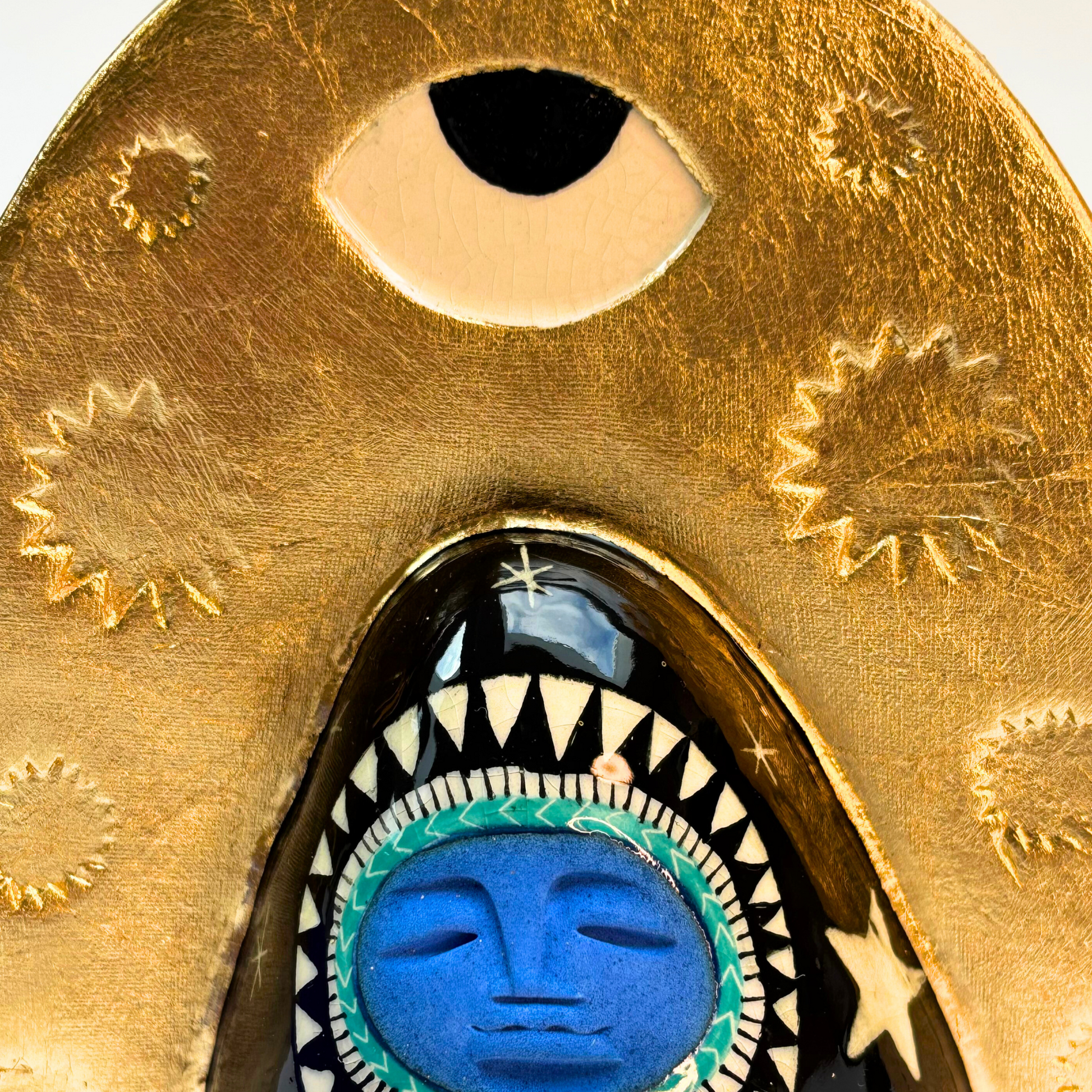 close up of the ye at the top of the gold crown in white with black pupil
