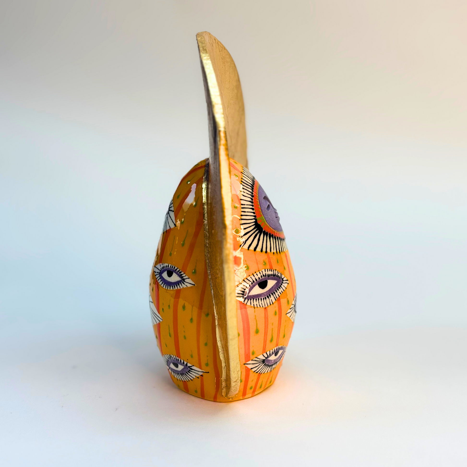 side view 16cm ceramic goddess with lavender colour face and eye design on body with gold crown
